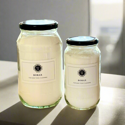 Two clear glass jars, one larger (2Litres) and one smaller (1litre). They both have simple white label with Under your Sink Logo and description Borax- all round Eco-cleaner – mid strength alkali. They are filled with white crystalline Borax granules inside. Background is of a kitchen and its a clean image to show green cleaning. This is a product image for website as this is for sale in various sizes, online with Australia wide delivery.